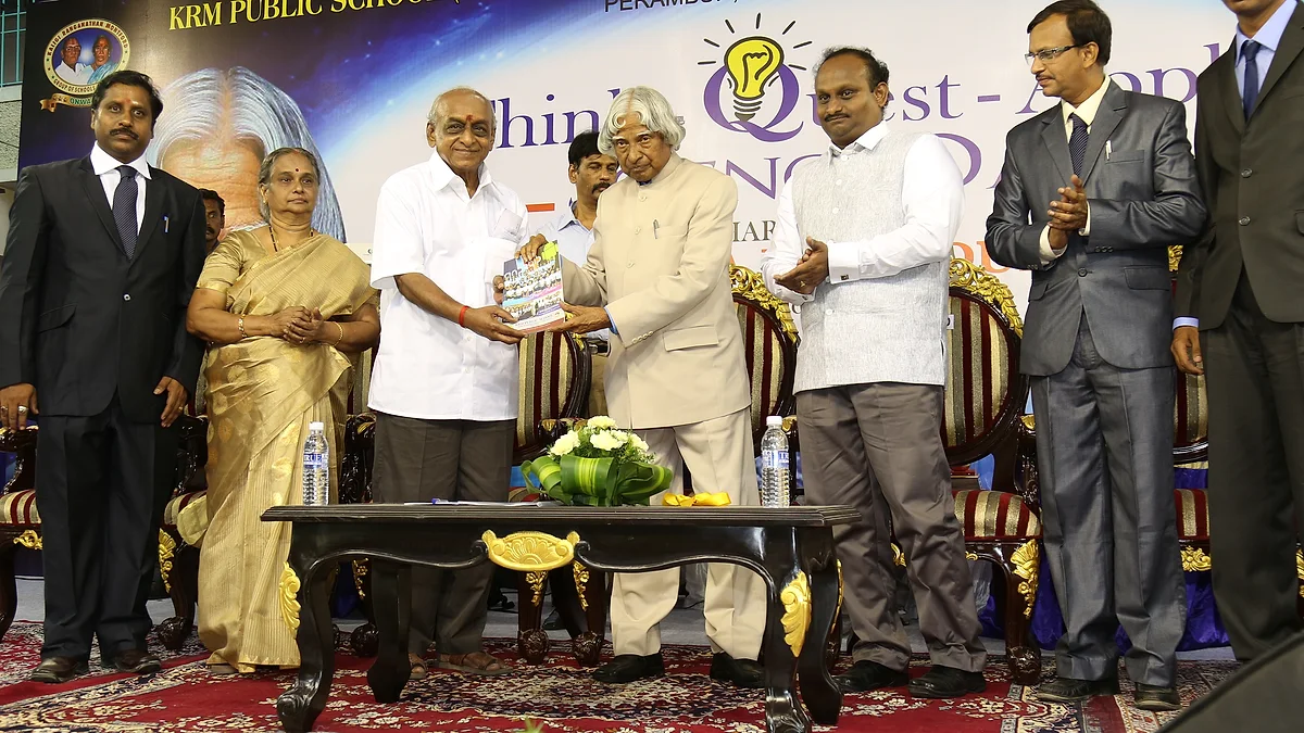 Dr. A.P.J. Abdul Kalam receiving a book on the KRM Public School stage, with R.J. Bhuvanesh standing alongside